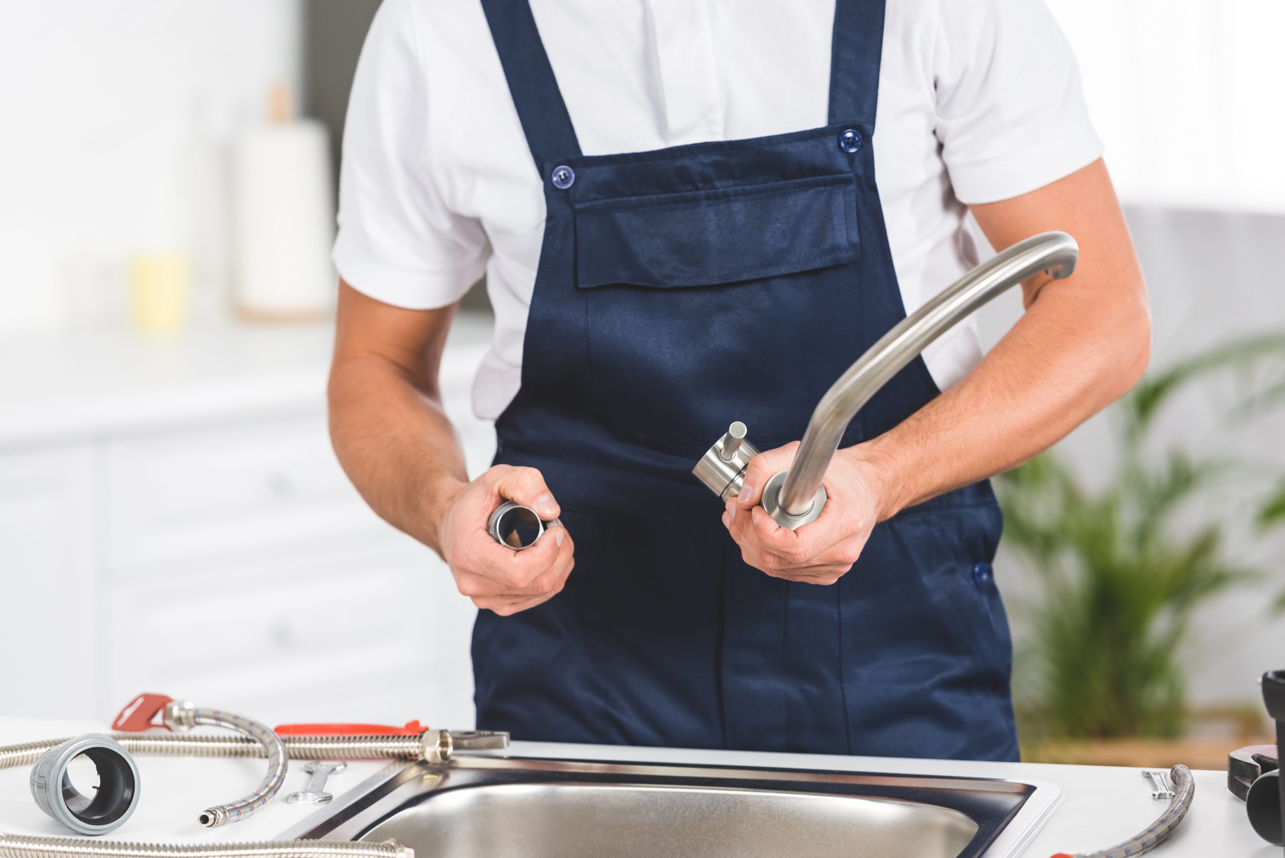 cropped view of repairman taking off kitchen faucet for repairing