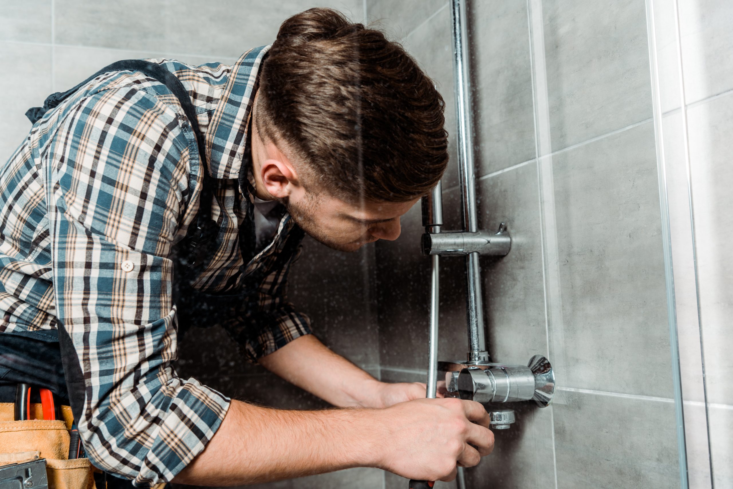 installer touching metallic pipe in bathroom