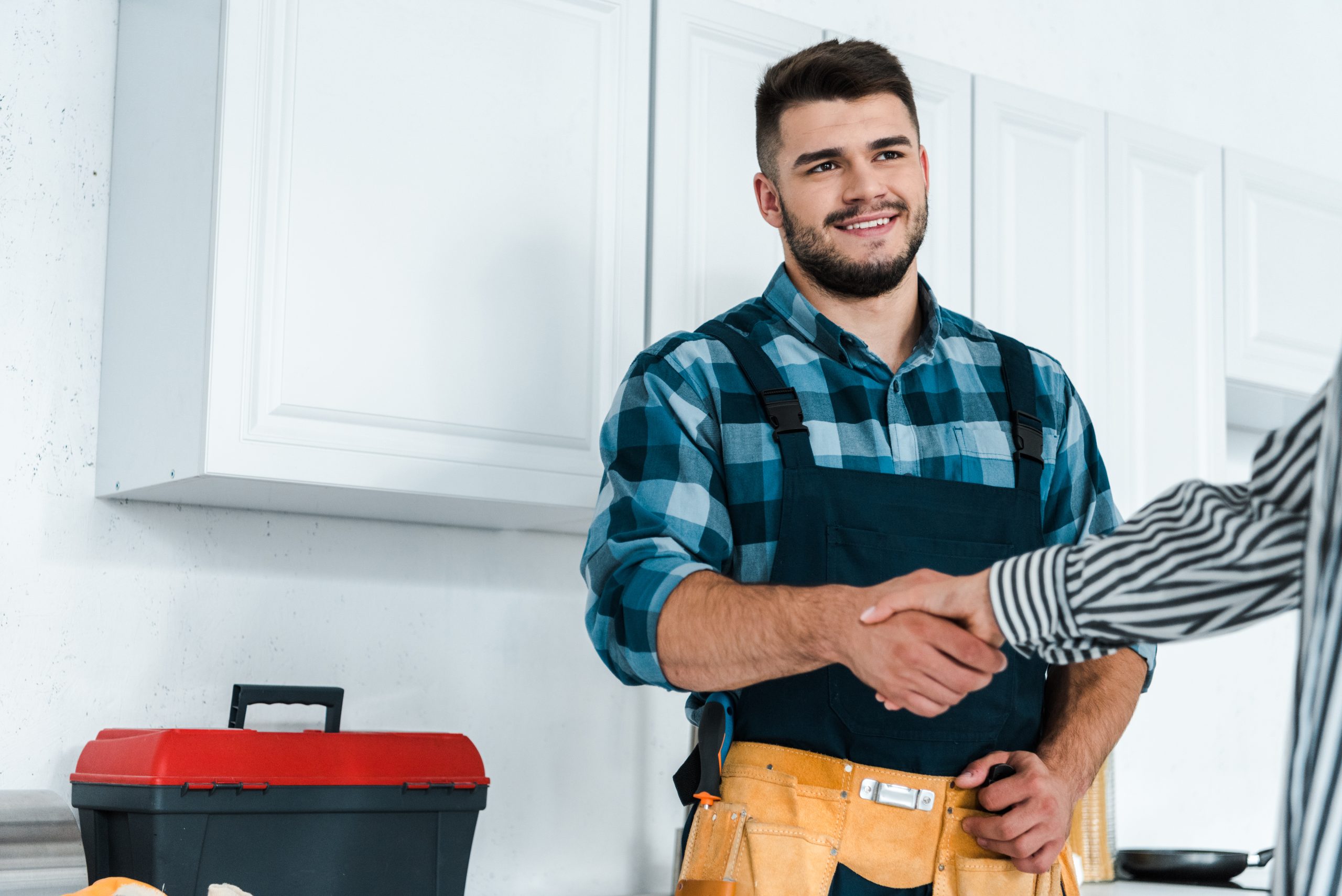 cropped view of woman shaking hands with happy bearded handyman