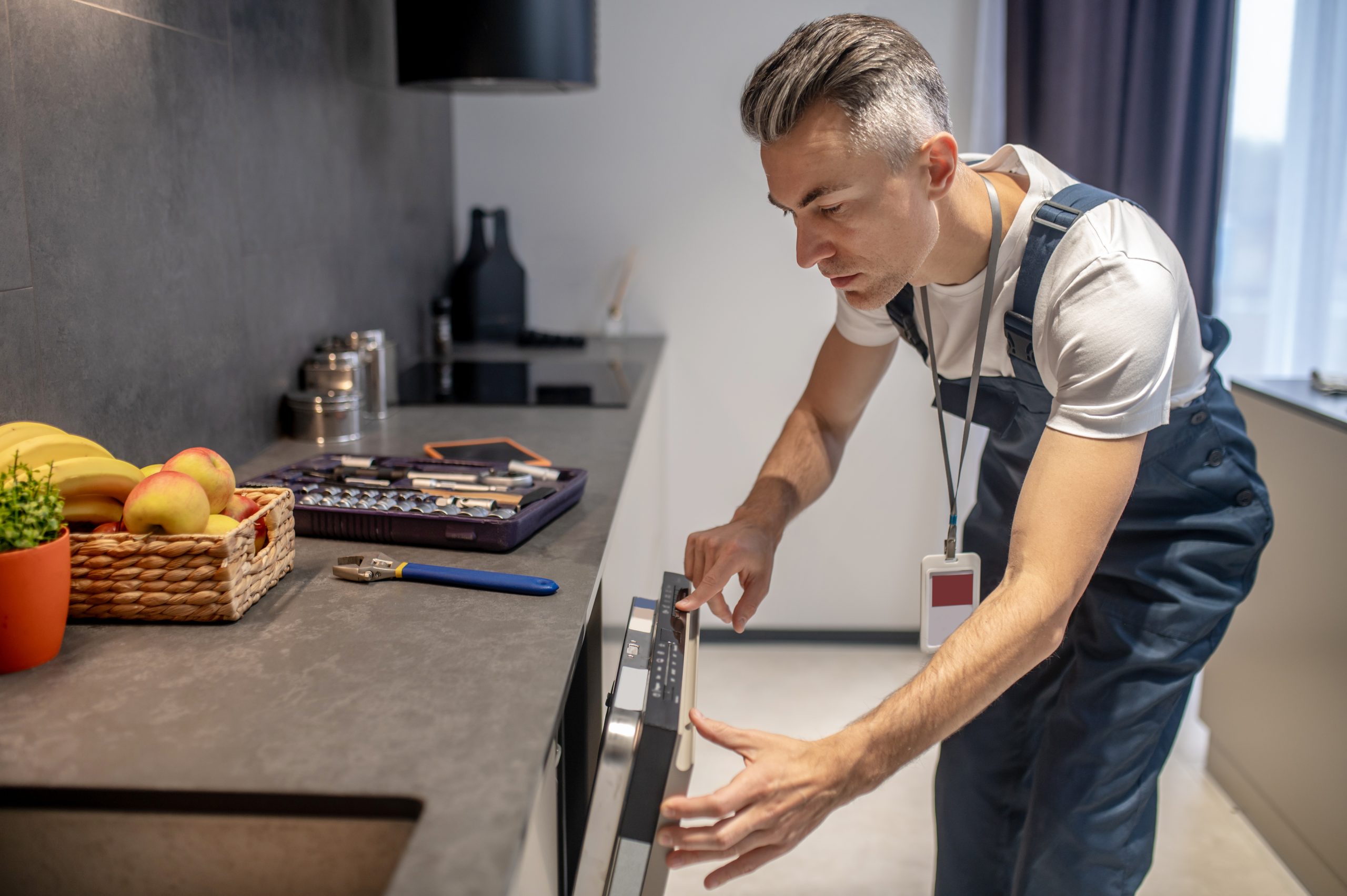 man looking at information on control panel of dishwasher