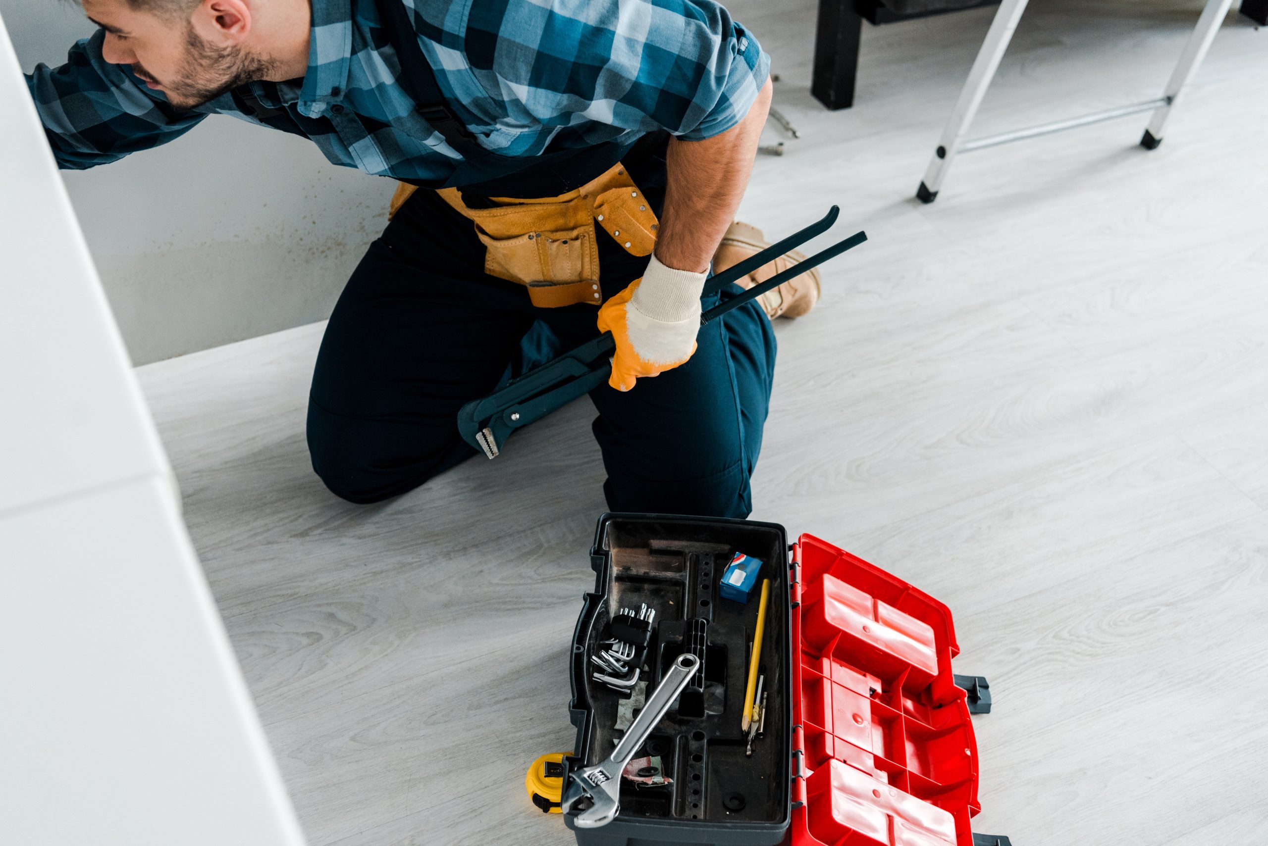 overhead view of bearded man working in kitchen near toolbox with instruments